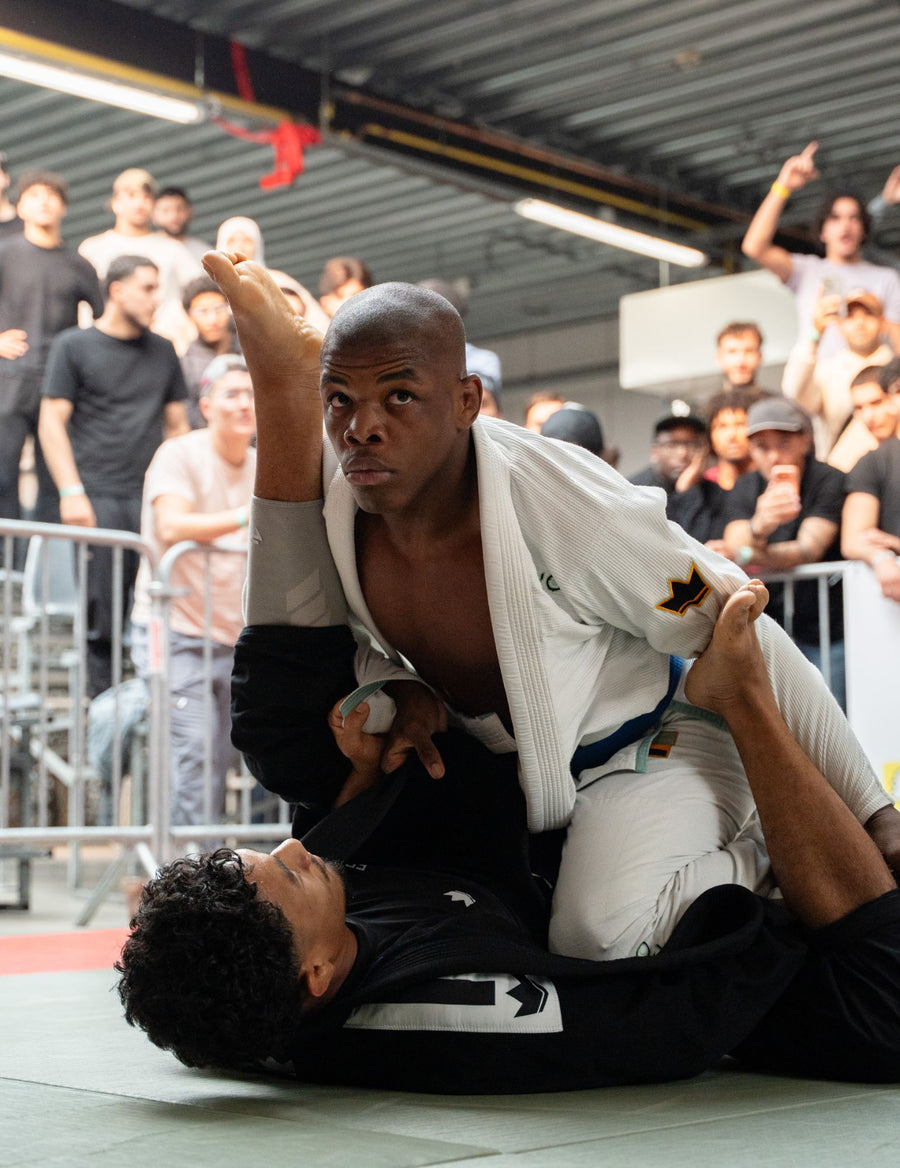 Combattant de JJB en garde, doigts tapés, devant le public