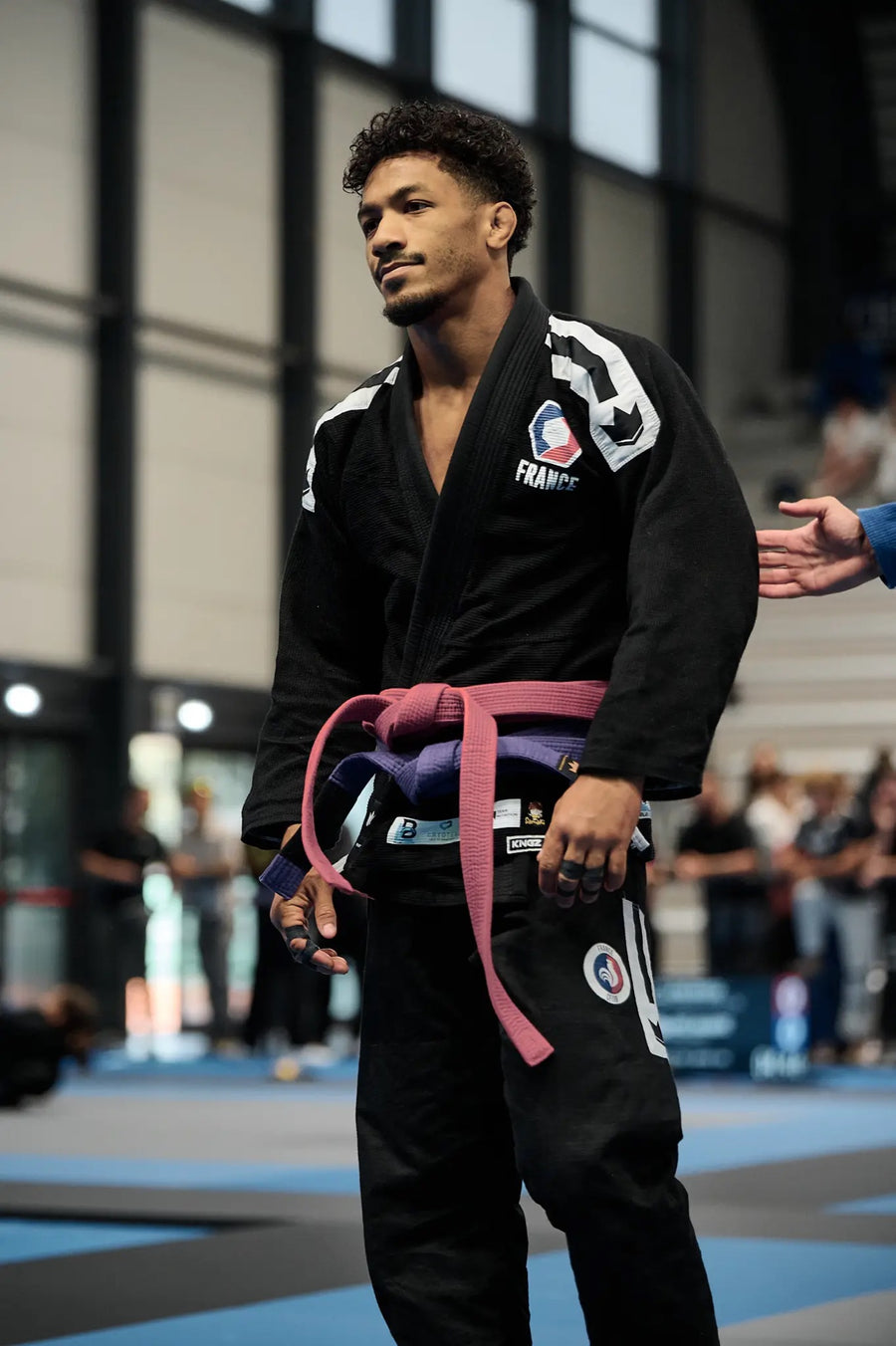 Combattant de JJB en kimono noir ceinture violette en compétition